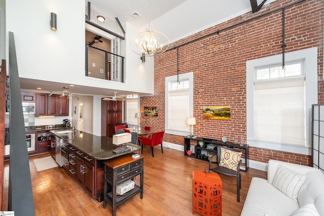 kitchen featuring pendant lighting, brick wall, sink, and light hardwood / wood-style flooring