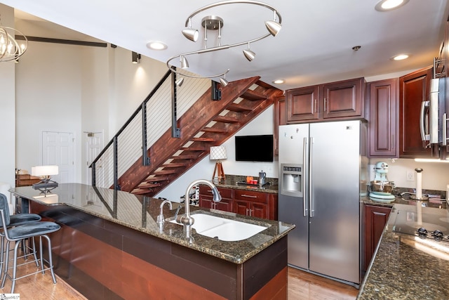 kitchen featuring sink, light hardwood / wood-style flooring, a breakfast bar area, appliances with stainless steel finishes, and dark stone countertops