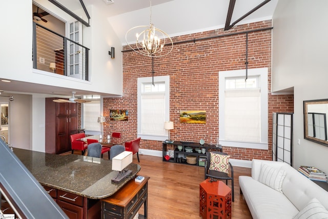 interior space featuring brick wall, a towering ceiling, a wealth of natural light, and light wood-type flooring