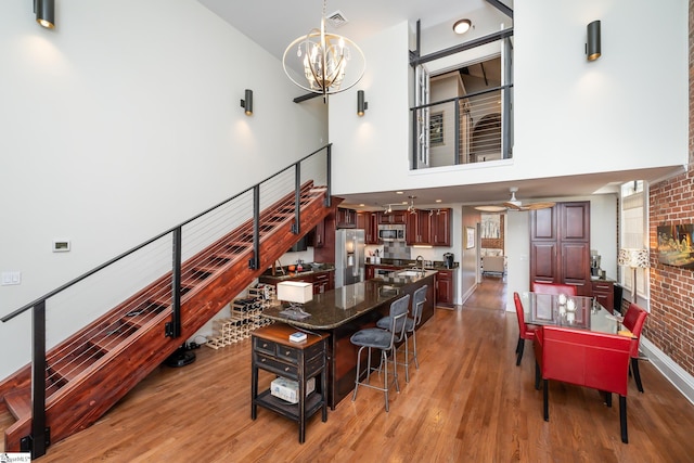 interior space with a high ceiling, sink, ceiling fan with notable chandelier, and light hardwood / wood-style flooring