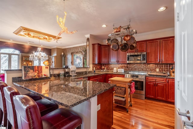 kitchen featuring pendant lighting, kitchen peninsula, dark stone countertops, and appliances with stainless steel finishes