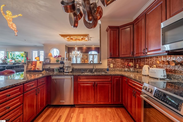 kitchen with dark stone countertops, sink, decorative light fixtures, and appliances with stainless steel finishes