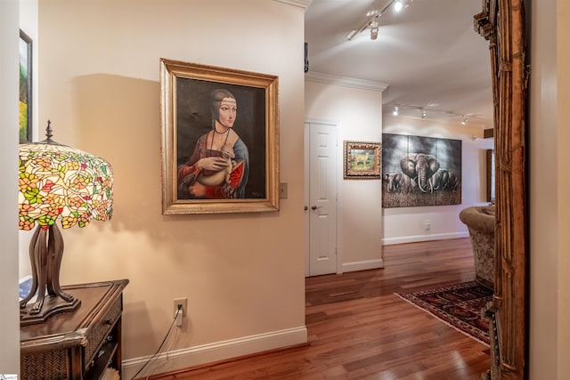 corridor featuring hardwood / wood-style flooring, ornamental molding, and track lighting