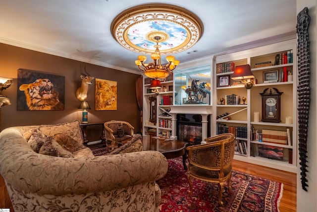 sitting room with ornamental molding, wood-type flooring, and a notable chandelier