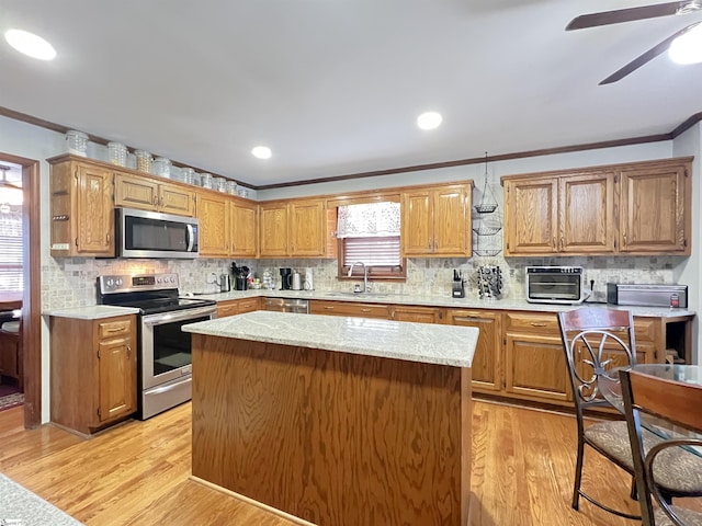 kitchen with appliances with stainless steel finishes, sink, a center island, crown molding, and light hardwood / wood-style flooring