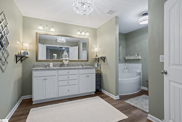 bathroom featuring vanity, a bathing tub, hardwood / wood-style floors, and a notable chandelier