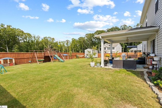 view of yard with a playground, outdoor lounge area, ceiling fan, and a storage shed