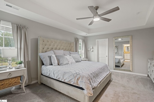 carpeted bedroom featuring a raised ceiling and ceiling fan