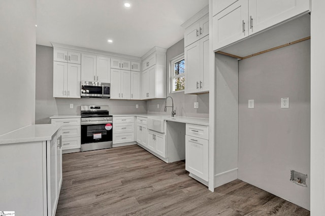 kitchen with white cabinetry, sink, stainless steel appliances, and light hardwood / wood-style floors