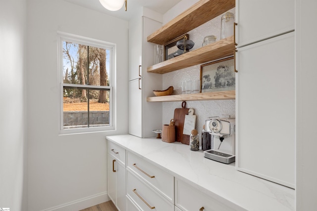 bar with white cabinetry and light stone countertops