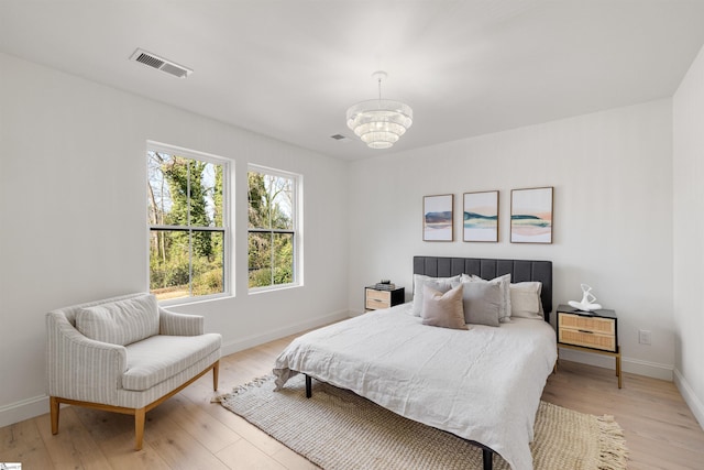 bedroom with an inviting chandelier and light hardwood / wood-style floors