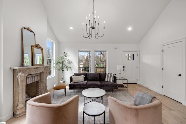 living room featuring an inviting chandelier, a brick fireplace, light hardwood / wood-style flooring, and high vaulted ceiling