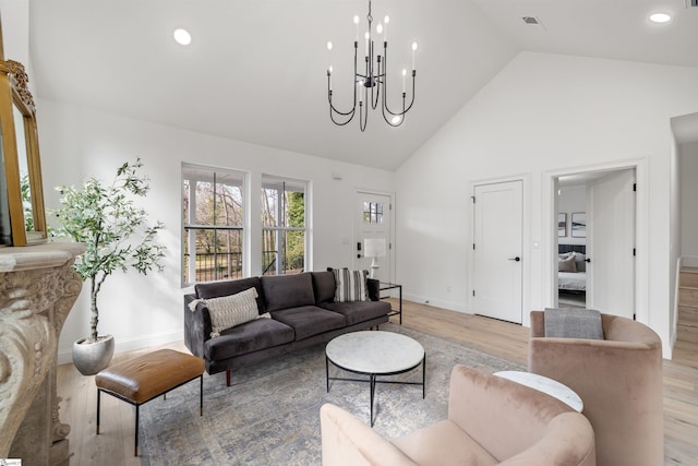 living room with an inviting chandelier, high vaulted ceiling, and light hardwood / wood-style flooring