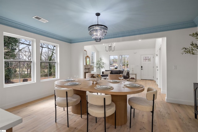 dining area featuring plenty of natural light, ornamental molding, a chandelier, and light wood-type flooring