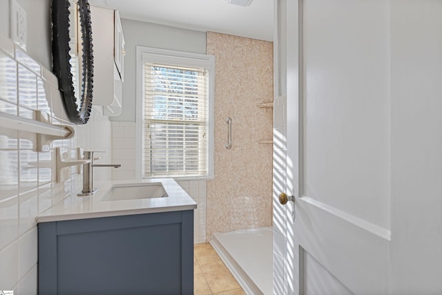 bathroom with vanity, tile patterned flooring, tile walls, and a shower