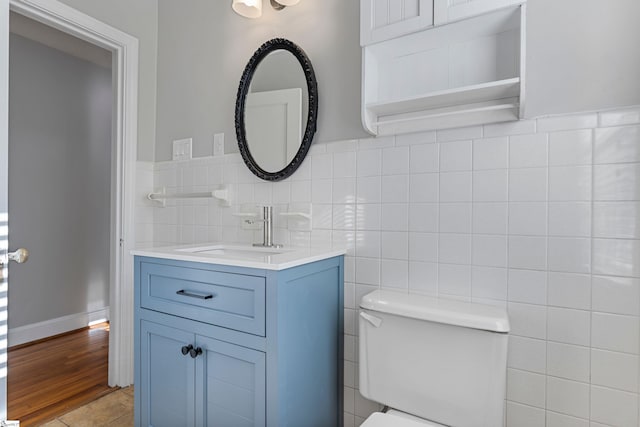 bathroom featuring vanity, tile walls, and toilet