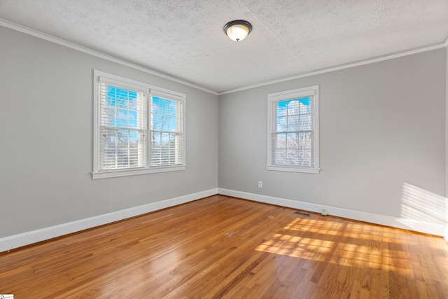 spare room with wood-type flooring, ornamental molding, and a textured ceiling