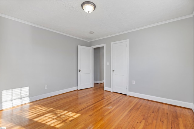 empty room with crown molding, a textured ceiling, and light wood-type flooring