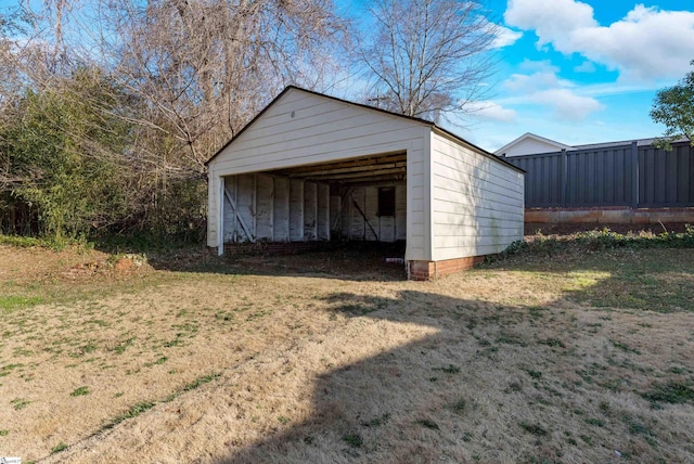 garage featuring an outdoor structure and a lawn