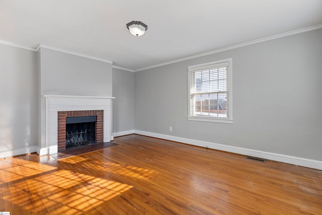 unfurnished living room featuring a brick fireplace, ornamental molding, and hardwood / wood-style floors