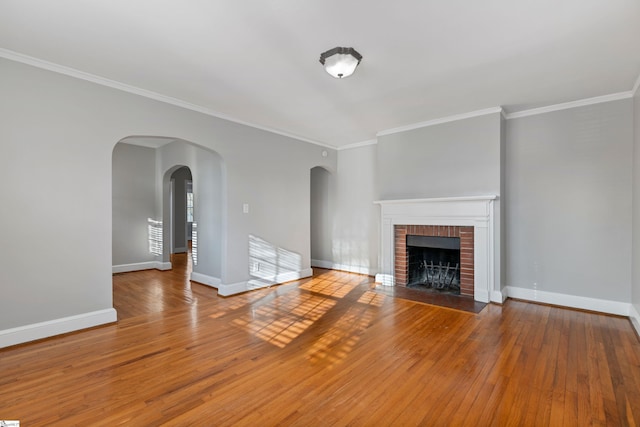 unfurnished living room featuring a brick fireplace, wood-type flooring, and ornamental molding