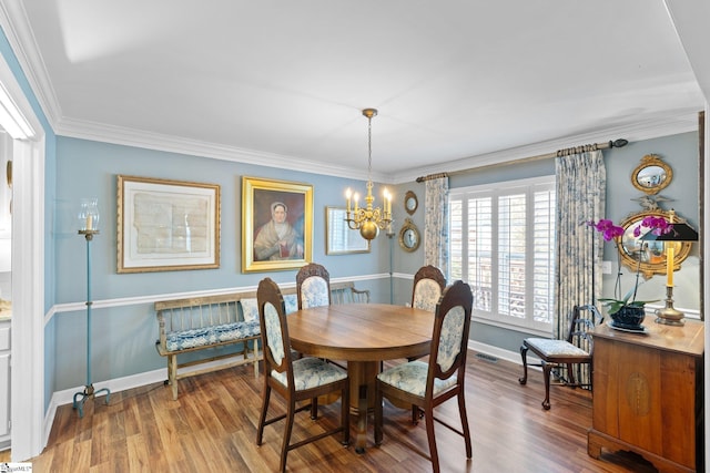 dining area with wood-type flooring, ornamental molding, and a notable chandelier