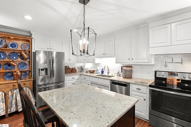 kitchen with sink, appliances with stainless steel finishes, white cabinetry, a center island, and decorative light fixtures