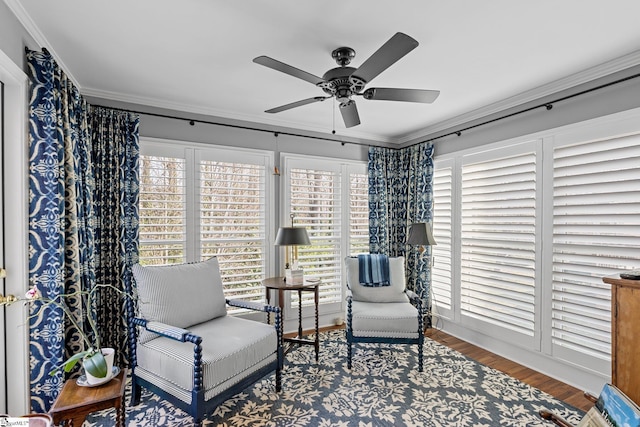 living area featuring hardwood / wood-style floors, ornamental molding, and ceiling fan