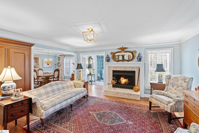 living room featuring plenty of natural light, hardwood / wood-style floors, a fireplace, and an inviting chandelier