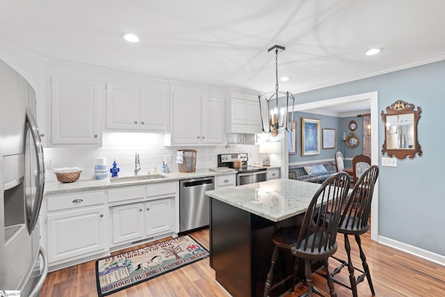 kitchen featuring a kitchen island, pendant lighting, white cabinetry, sink, and stainless steel appliances