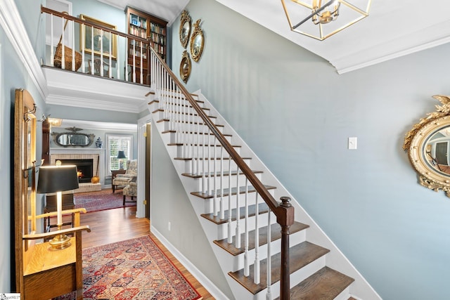 stairway featuring ornamental molding, a brick fireplace, and hardwood / wood-style floors