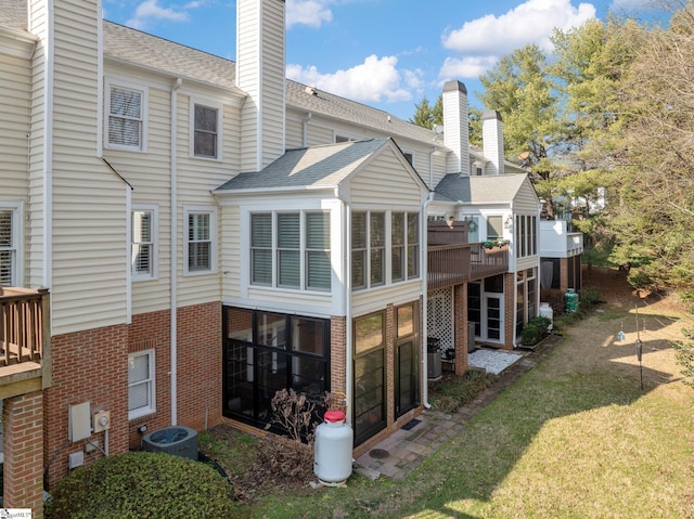 back of property featuring a sunroom, central AC, and a lawn