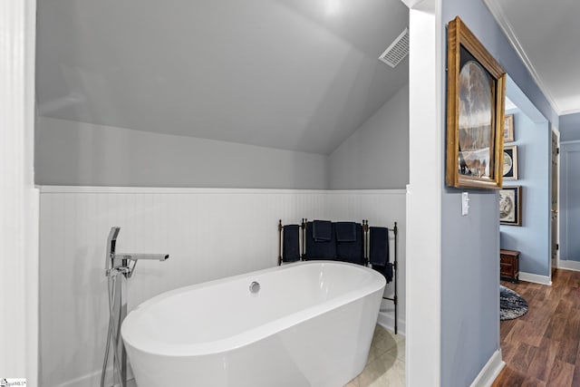 bathroom featuring a tub to relax in, vaulted ceiling, and hardwood / wood-style floors