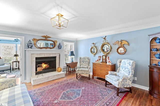 sitting room featuring hardwood / wood-style flooring, crown molding, and a brick fireplace