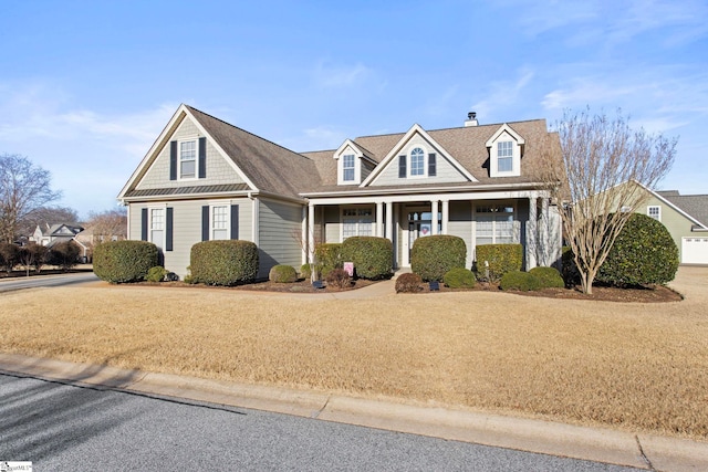 cape cod home featuring a front yard and covered porch