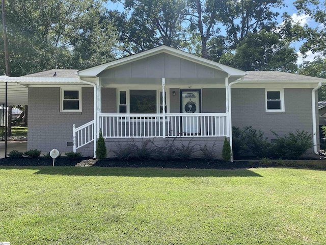 view of front of home featuring covered porch, a front lawn, an attached carport, and brick siding