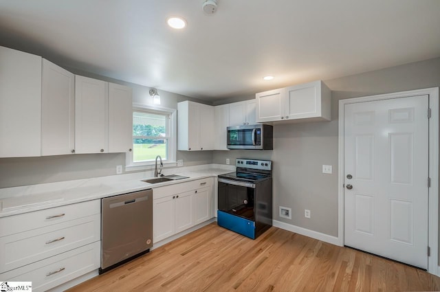 kitchen featuring stainless steel appliances, light wood-style floors, a sink, and white cabinets