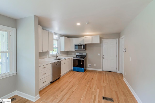 kitchen featuring visible vents, white cabinets, appliances with stainless steel finishes, light countertops, and a sink