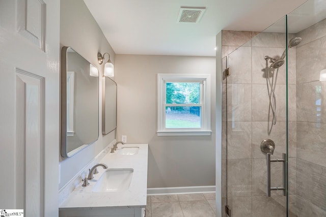 bathroom with a stall shower, a sink, visible vents, and baseboards