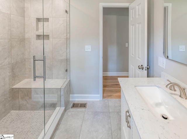 bathroom with tiled shower, vanity, and tile patterned flooring