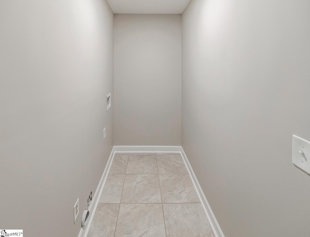 interior space with laundry area, baseboards, and light tile patterned flooring