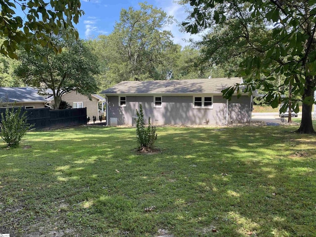 rear view of house featuring a yard and fence