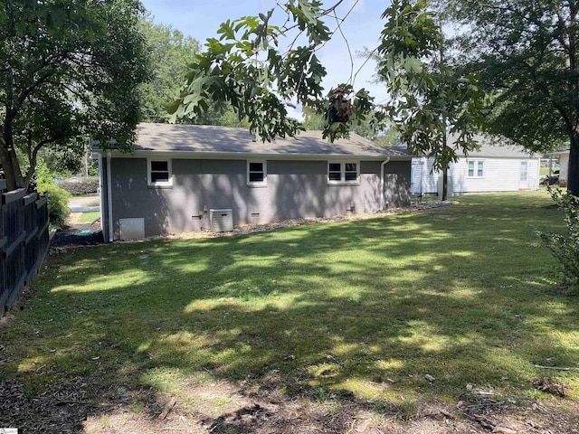 rear view of property with crawl space, central AC, fence, and a lawn