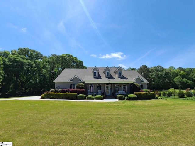 new england style home featuring covered porch and a front lawn