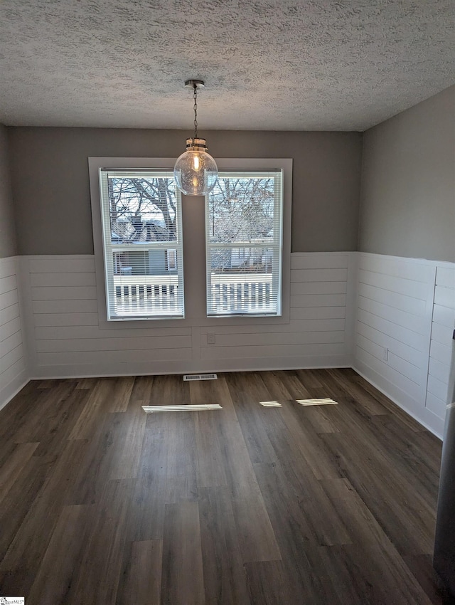 unfurnished dining area with dark hardwood / wood-style floors and a textured ceiling