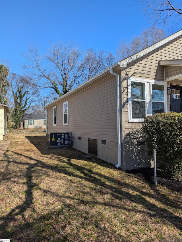 view of side of property with crawl space and a yard