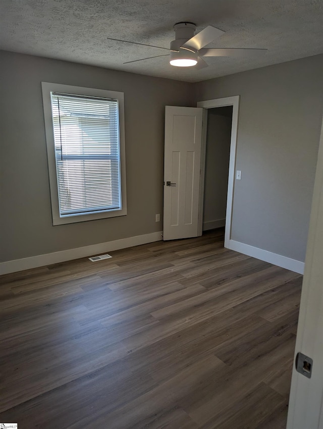 empty room featuring ceiling fan, dark hardwood / wood-style floors, and a textured ceiling