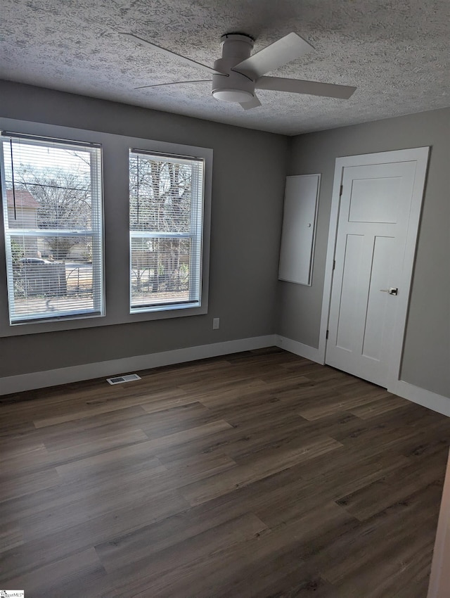 unfurnished room with ceiling fan, dark hardwood / wood-style floors, and a textured ceiling