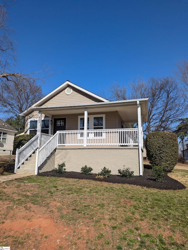 view of front facade featuring a front yard, covered porch, and stairs