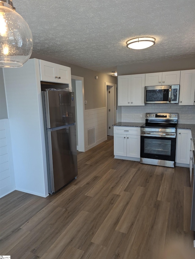 kitchen featuring stainless steel appliances, white cabinetry, dark wood-type flooring, and a textured ceiling